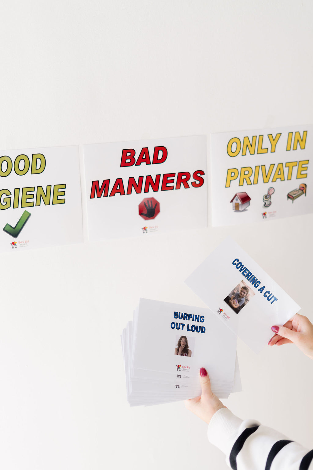 Good Hygiene / Bad Manners category cards on a wall, alternate angle, with behaviour cards held below